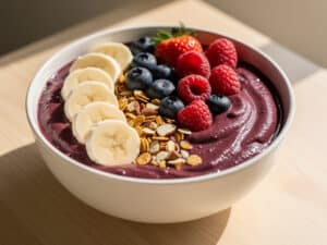 Cremige Açaí Bowl mit Bananenscheiben, Beeren, Granola und Nüssen